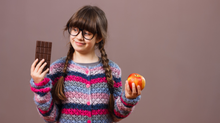 Girl choosing between chocolate or apple