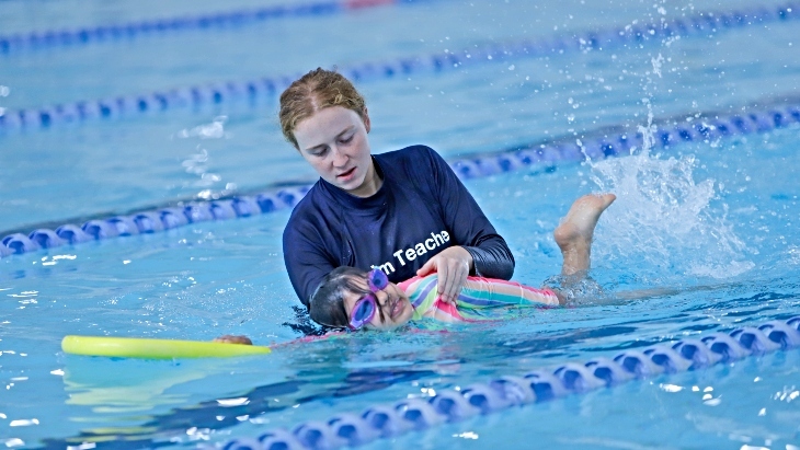 A swimming instructor and child in the pool