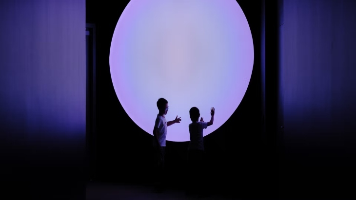 Two children touch a purple circular light display