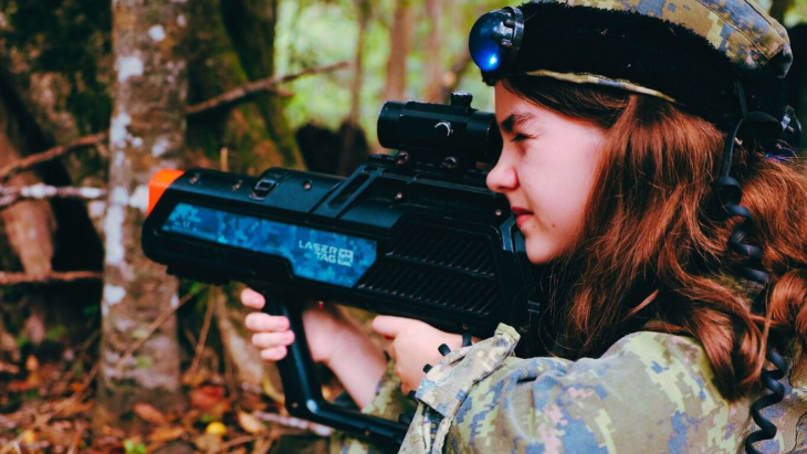 Young girl in combat gear plays laser tag 