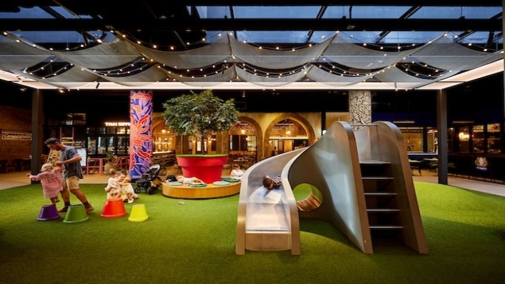 Indoor slide, a dad helps child play on coloured stepping stones