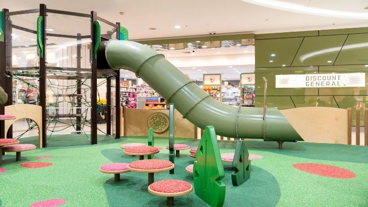 Indoor play centre with astro-turf, a green slide and stepping stones 