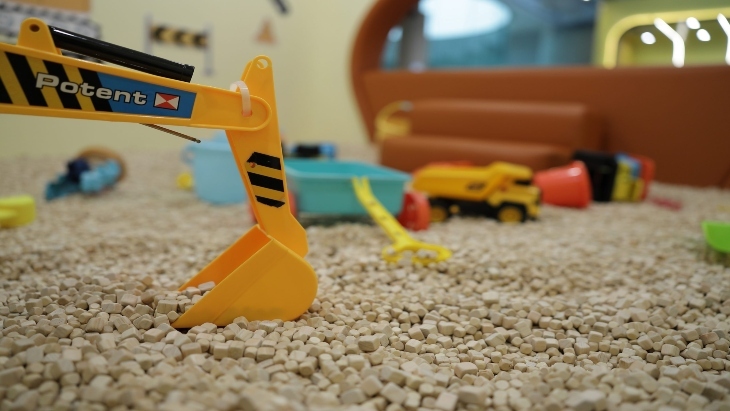 Mini yellow digger in sand in a kids playground 