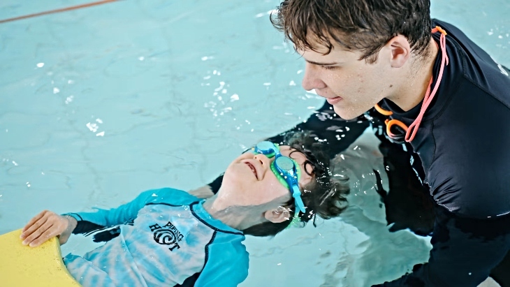 Child learning to swim with swim instructor