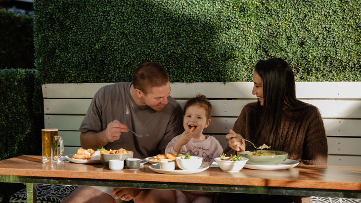 Two adults and a child eating in a restaurant