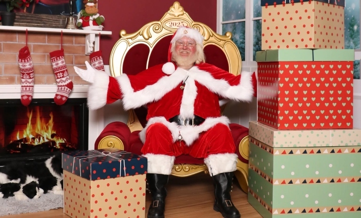 Santa smiling with open arms on a couch