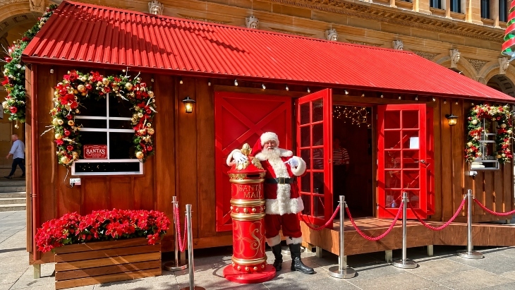 Santa standing outside a red house