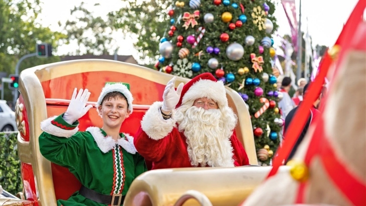 Santa in a sleigh with a boy dressed as an elf