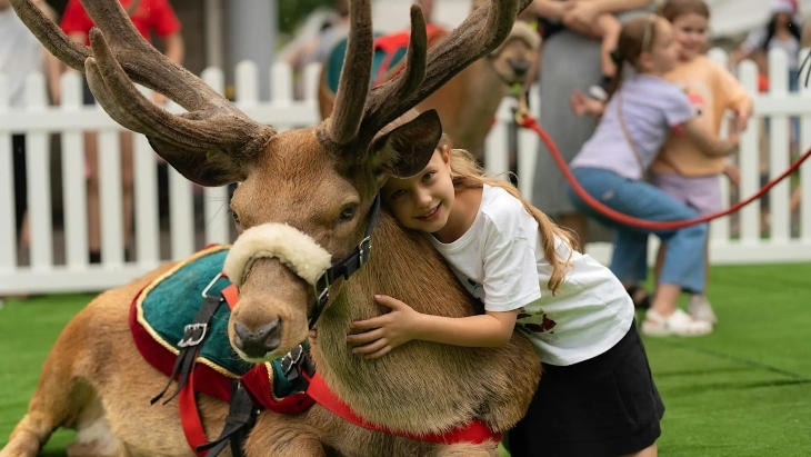 Little girl hugging a reindeer at Christmas