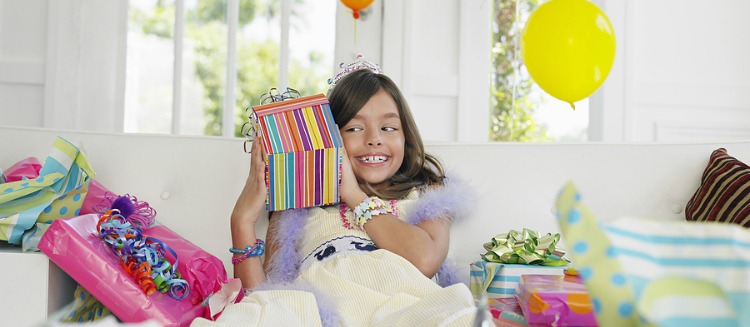 Cheerful young girl opening birthday presents in house