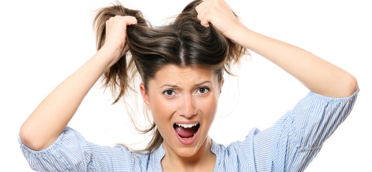 A portrait of a young frustrated woman pulling out hair over white background