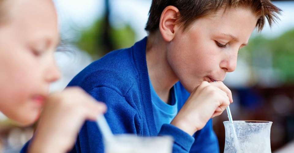 Kids brother and sister drinking milkshakes in outdoor cafe