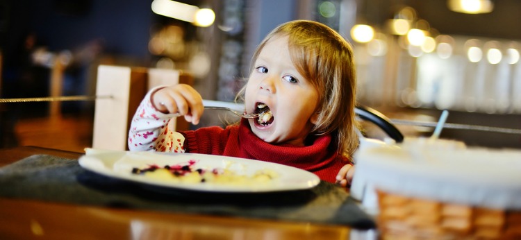 toddler girl is eating in the restaurant