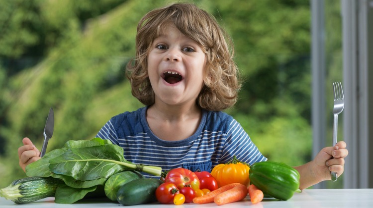 Cute little boy sitting at the table excited about vegetable meal bad or good eating habits nutrition and healthy eating showing emotions concept
